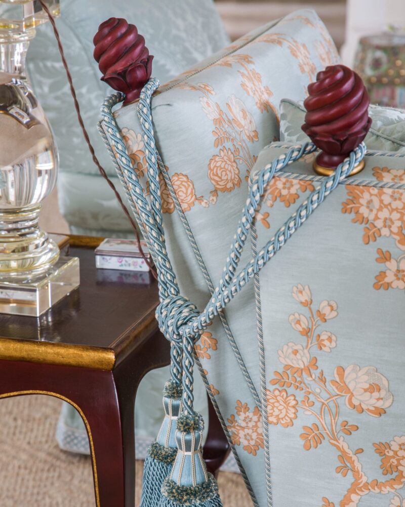 Elegant blue floral upholstery with decorative tassels and a wooden end table.