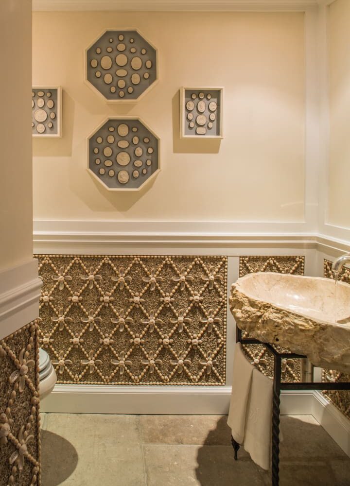 Elegant powder room with shell-patterned walls, stone sink, and geometric wall art.
