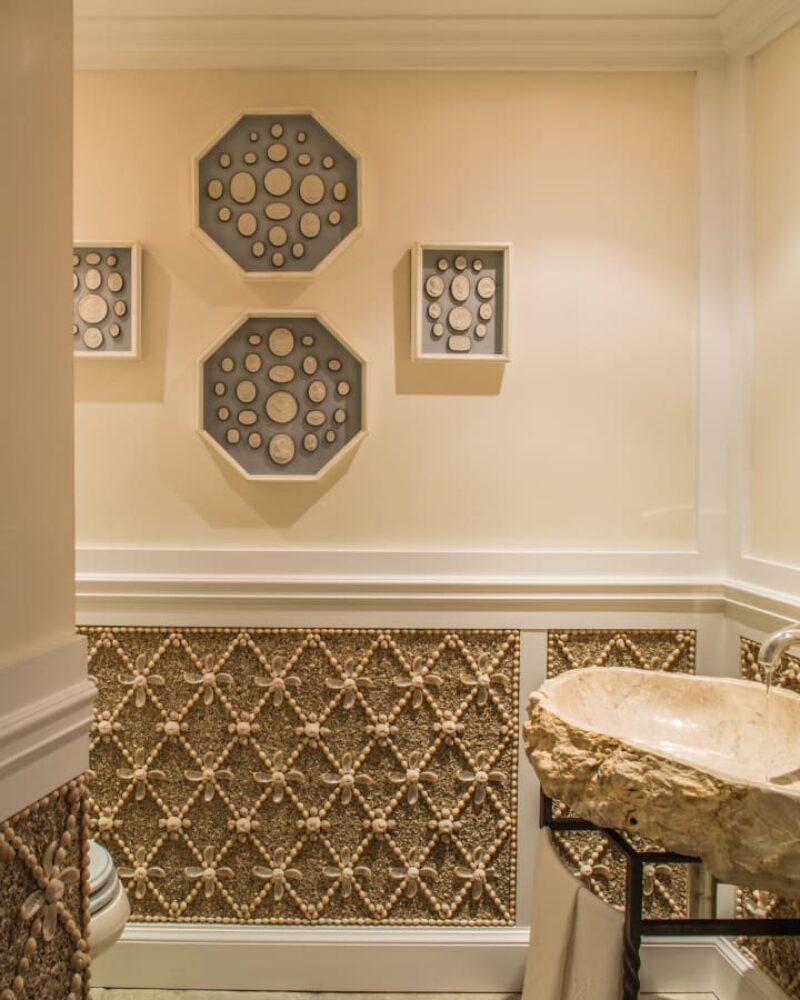 Elegant powder room with shell-patterned walls, stone sink, and geometric wall art.