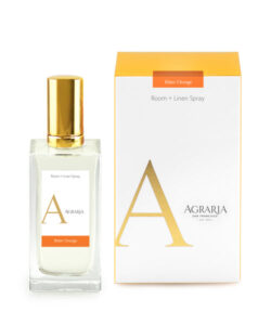 Clear glass bottle of Agraria Bitter Orange Room + Linen Spray next to its orange and white box.