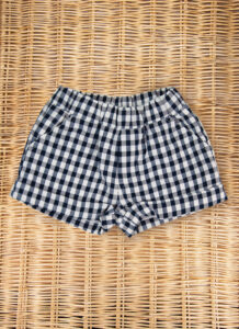 Navy and white checkered shorts laid flat on a woven surface.