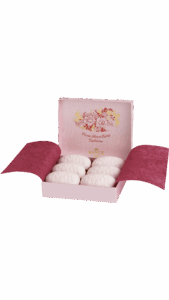 A pink box contains six intricately designed white soaps, labeled "Crème Savon Extra Tubéreuse.