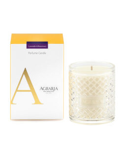 Lavender and rosemary perfume candle in a glass holder beside its yellow and white packaging.