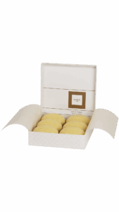 A white box opens to reveal six yellow soaps labeled "Crème Grasse.