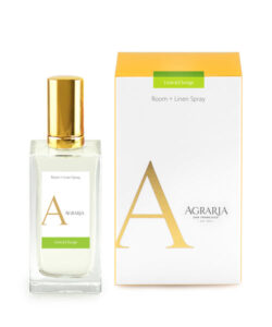 Clear glass bottle of Agraria Room + Linen Spray next to its yellow and white box, labeled "Lime & Orange.