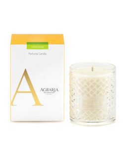 A clear glass candle with a textured design beside a yellow and white box labeled "Lime & Orange Perfume Candle.