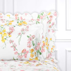 Floral-patterned bedding with pink and yellow flowers on a white background and scalloped edges.