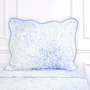 Light blue pillow with floral pattern rests on a matching bedspread against a white backdrop.