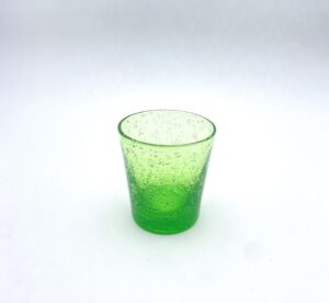 A translucent green glass with bubbles, sitting on a white background.