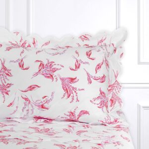 Pink scalloped bed linen features floral patterns on a white background.