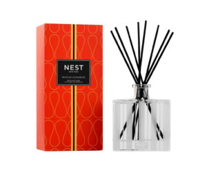 Reed diffuser with black sticks beside a vibrant red box labeled "Sicilian Tangerine.