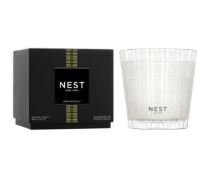Black box labeled "NEST Grapefruit" next to a clear, patterned glass candle.