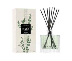 Reed diffuser with black sticks, green liquid, and a white box labeled "NEST Wild Mint & Eucalyptus.