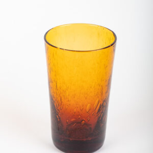 A tall, amber-colored glass with a textured surface, reflecting light.