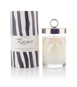 Scented candle in a glass jar beside a decorative striped box.