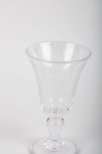 Clear glass with a flared top and bubbles, standing on a round base.