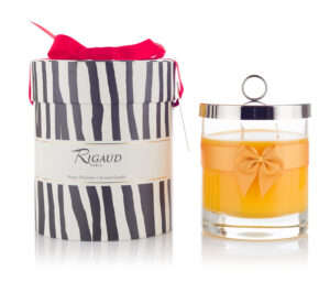 Scented candle in a glass jar with an orange ribbon, next to a striped gift box with a pink bow.