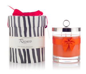 Scented candle in a glass jar with an orange ribbon, next to a striped gift box with a red bow.