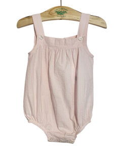 Pink and white seersucker romper with button details, hanging on a wooden hanger.