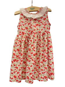 Red flower print dress with a white ruffled collar, hanging on a wooden hanger.