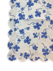 Blue clover patterns on a white fabric with a scalloped edge.