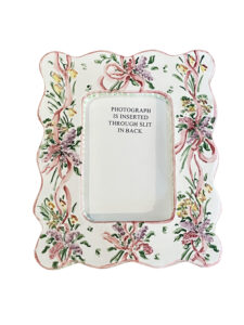 Decorative picture frame with floral design and pink ribbon, featuring a slot for inserting a photograph.