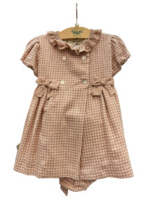 Pink gingham dress with ruffled collar and bows, hanging on a wooden display.