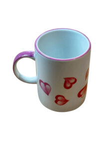 Ceramic mug with a pink handle and heart designs in various shades of red.