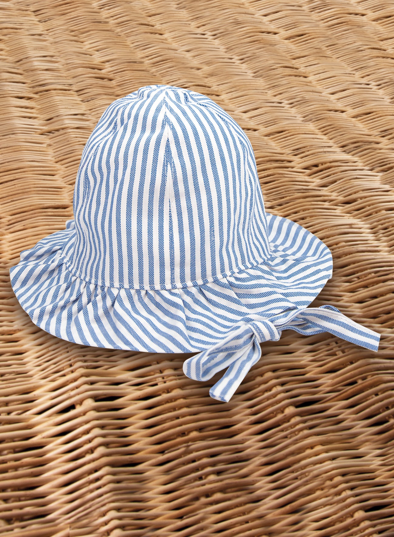 10596_cele_riga_1800x1800 A blue and white striped sun hat rests on a woven surface.