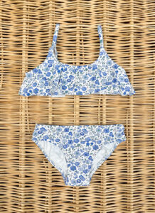 A floral bikini set with blue and white patterns, laid on a woven surface.