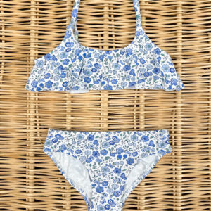 A floral bikini set with blue and white patterns, laid on a woven surface.
