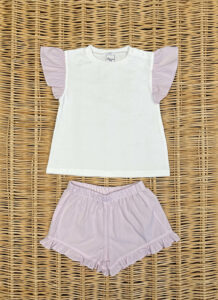A white shirt with pink ruffled sleeves paired with matching pink shorts on a woven surface.