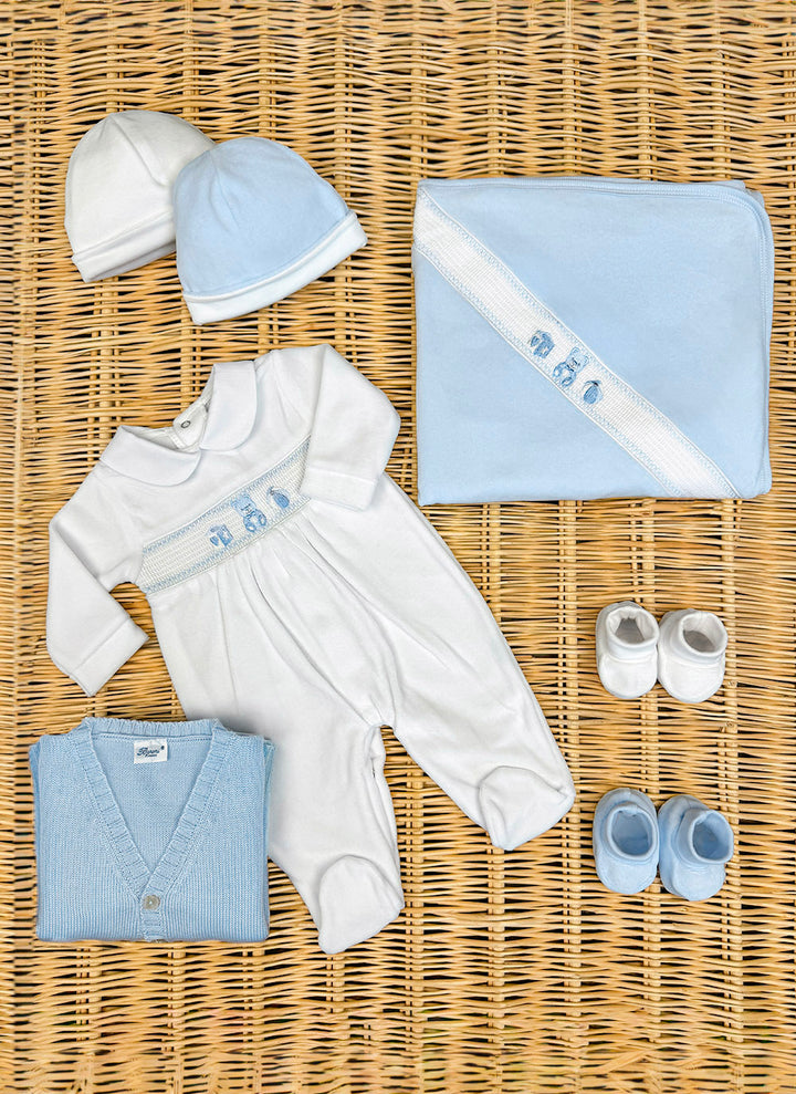 11489cielo_3_720x A collection of baby clothing: two hats, a onesie, a blanket, a sweater, and two pairs of shoes, all in blue and white.