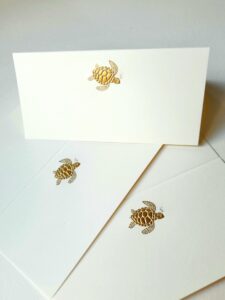 Three white cards feature embossed gold turtle designs on the front.
