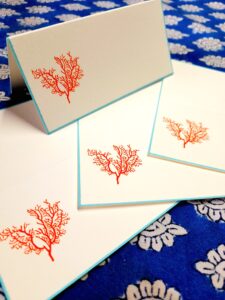A set of greeting cards featuring red coral designs on white backgrounds with blue edges.
