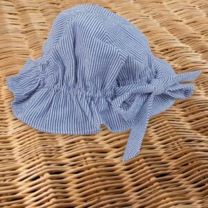 A blue and white striped sun hat rests on a woven surface.