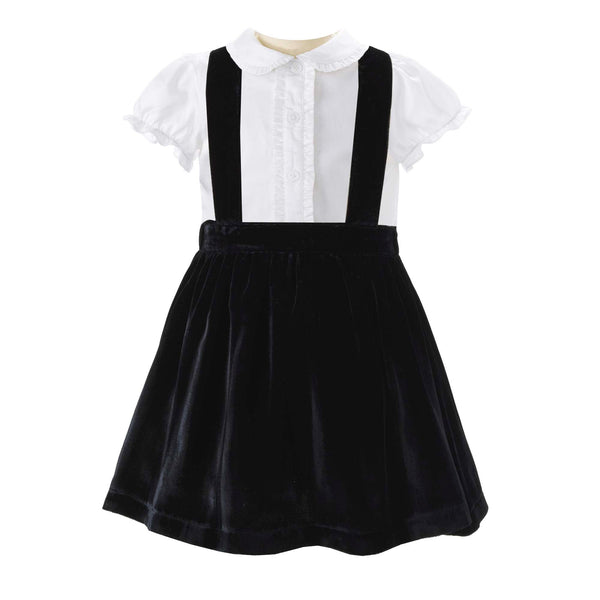 Black velvet dress with white collared shirt and suspenders, featuring a pleated skirt.