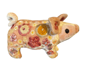 A plush piglet in old rose velvet, adorned with colorful floral embroidery.