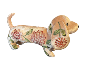 A plush dachshund with floral embroidery in pink and green, standing on a black background.