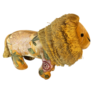 A plush lion with a golden mane and floral embroidery on its body.