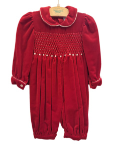 Red velvet romper with smocked bodice, puffed sleeves, and buttoned cuffs.