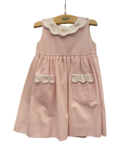 Pink and white seersucker dress with rose embroidery and scalloped collar, featuring two front pockets.