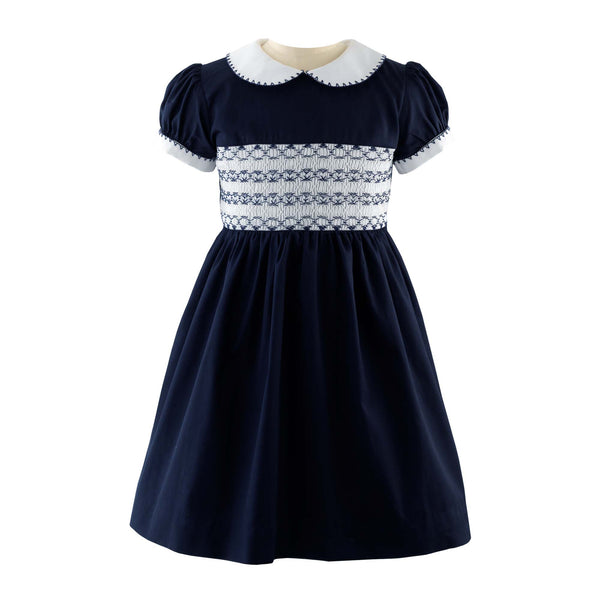 Navy blue smocked dress with puff sleeves and white collar, featuring intricate embroidery on the bodice.