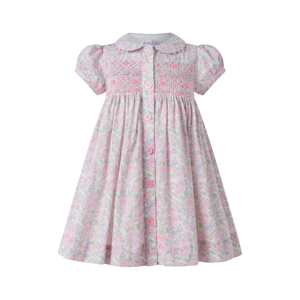 Light pink dress with short puff sleeves, smocked bodice, and floral pattern. Features a button-down front.