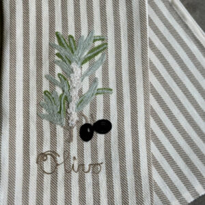 Embroidered olive branch and black olives on a striped fabric napkin. The word "Olive" is stitched below.