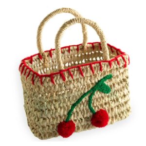 Woven straw basket with red trim and cherry design, featuring two handles.