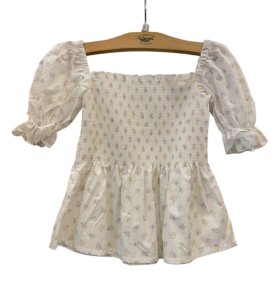 White floral top with puff sleeves and a smocked bodice, featuring a flared hem.