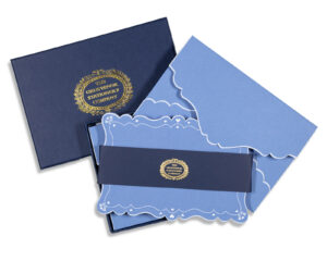 Navy box containing decorative blue stationery with a gold logo and intricate edges.