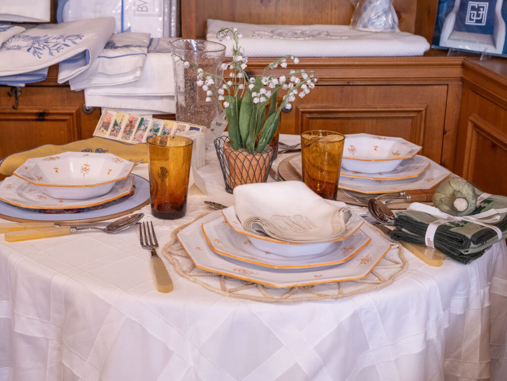 A beautifully set table with plates, glasses, utensils, and a small flower arrangement.