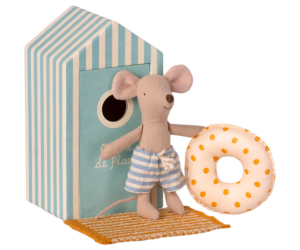 A mouse in striped shorts holds a polka-dotted float near a beach hut.